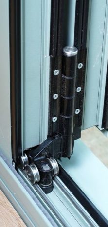 An image showing a close up of stainless steel rollers on a bifolding door