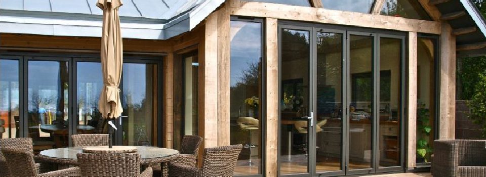 An image showing a new build property with bifolding doors in a traditional wooden structure.