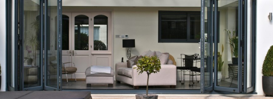 An image showing an interior view of a living room showing a cream leather sofa through a set of bifolding doors.